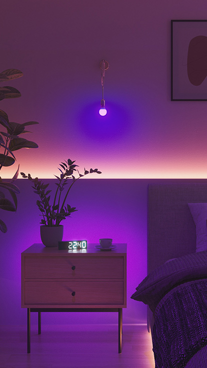 This is an image of Nanoleaf Essentials Bulb in a bedroom. The light fixture is on the wall in between the bed and nightstand and makes it the perfect bedroom light to set the ideal ambience.