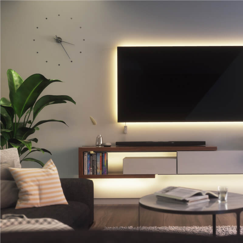 Nanoleaf Essentials Thread-enabled color-changing smart light strip mounted to a TV in a living room. Similar to Twinkly, Wyze. HomeKit, Google Assistant, Amazon Alexa, IFTTT.